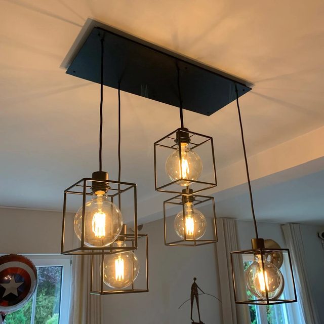 Suspensions cages en laiton avec ampoules à filament posées dans un séjour à Bruxelles